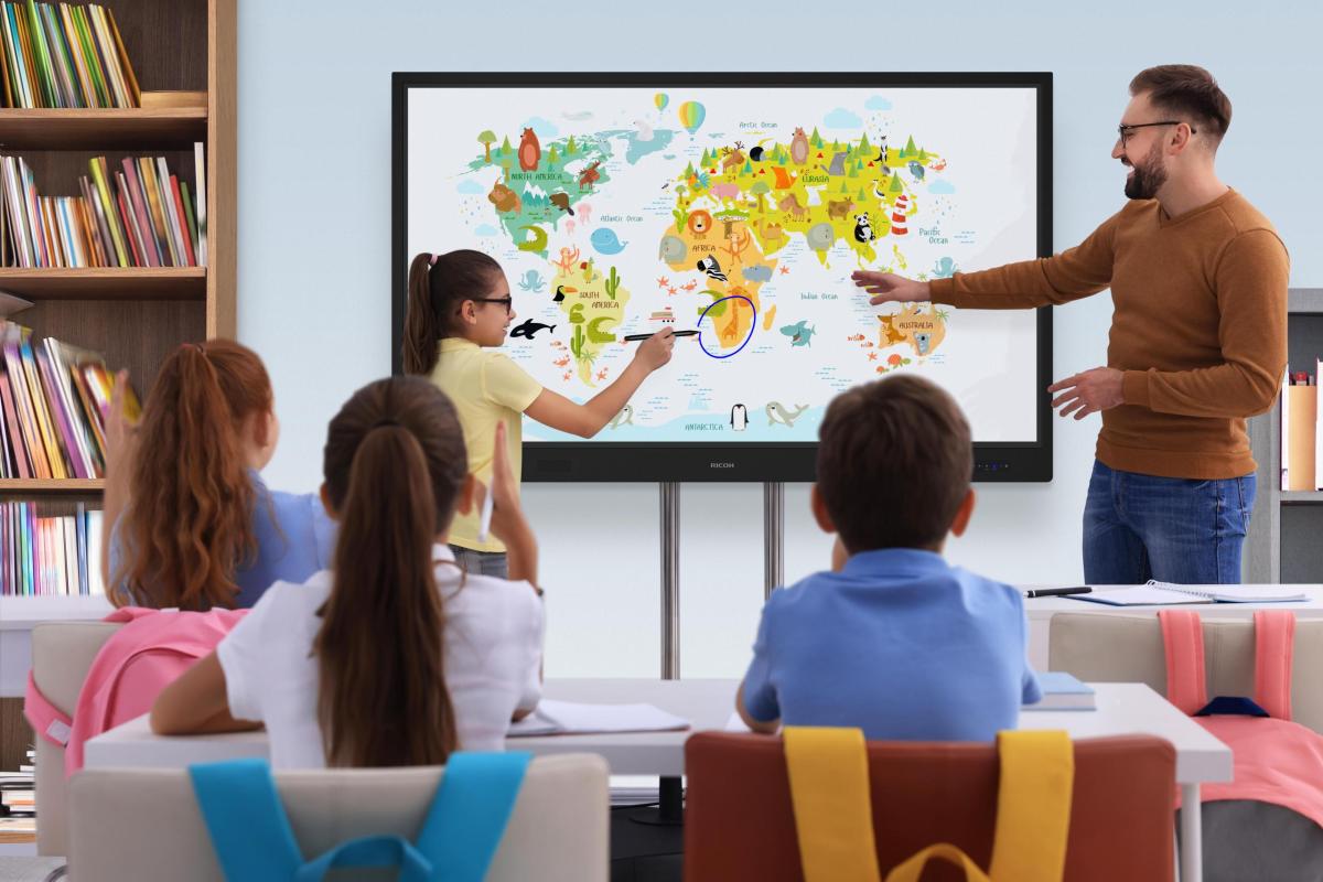 Teacher and pupil using interactive board in classroom during lesson